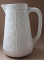 White pitcher for milk. Faience. Floral theme.